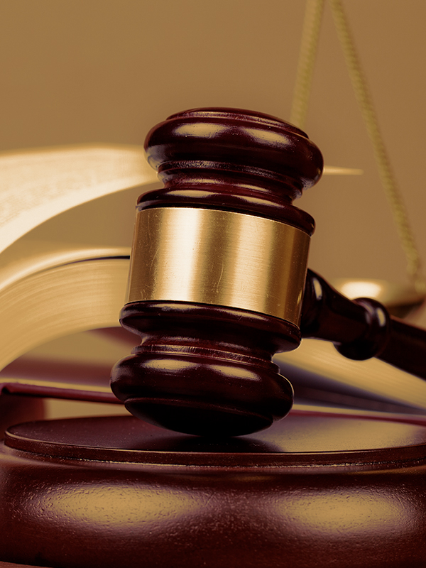 A wooden gavel on top of a legal book in a courtroom setting.