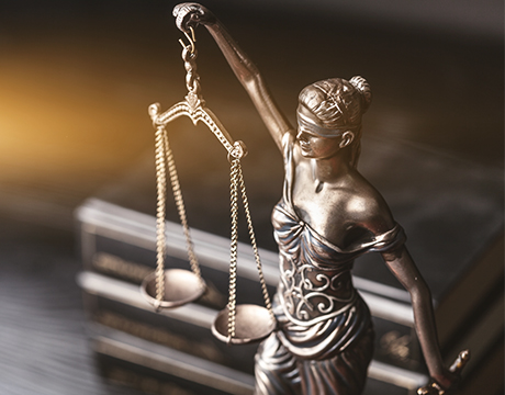 A figurine of Lady Justice holding balanced scales, blindfolded, on a wooden surface.
